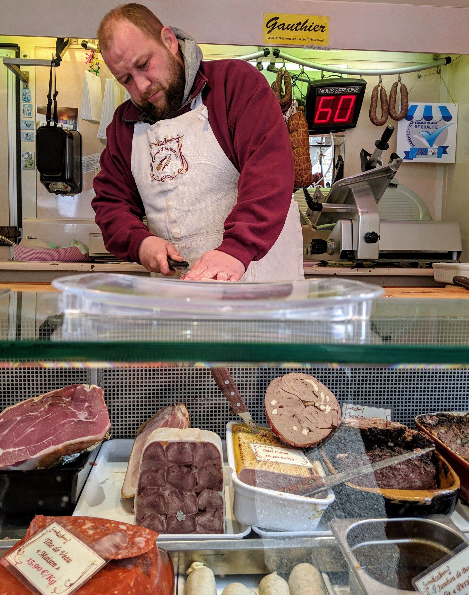 Gauthier Collin coupe une pièce derrière la vitrine de charcuteries maison